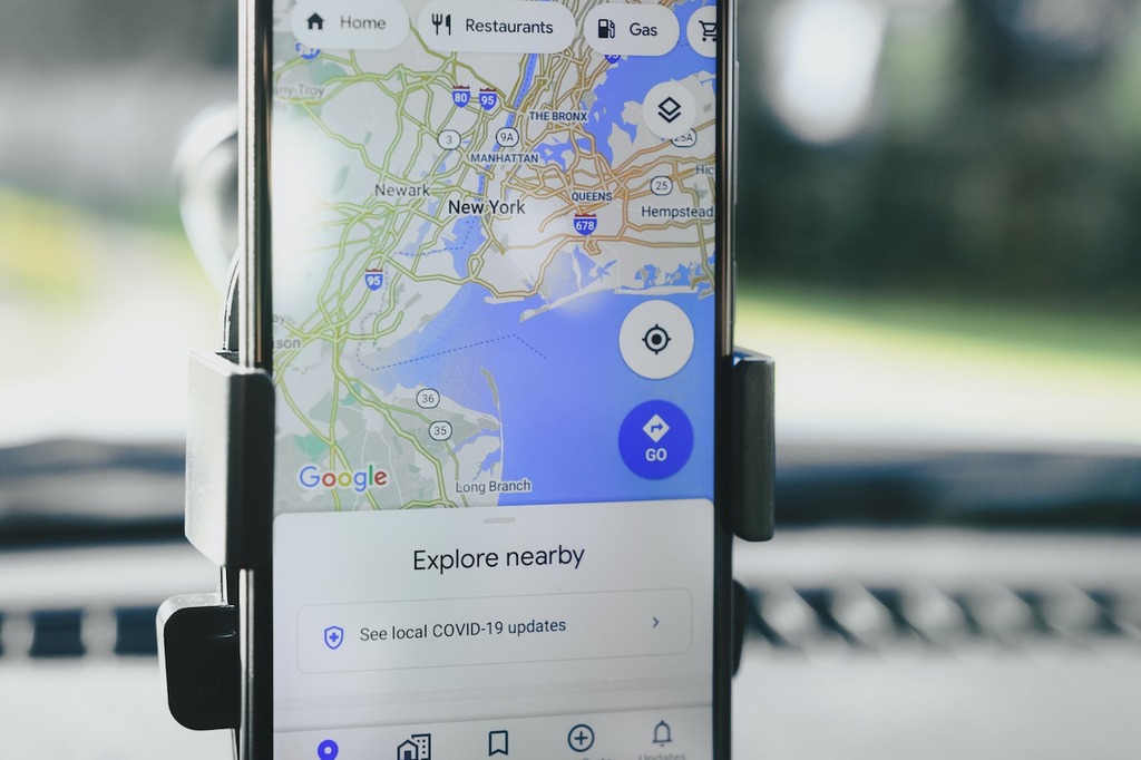 cell phone in a holder on the vehicle dashboard displaying google maps